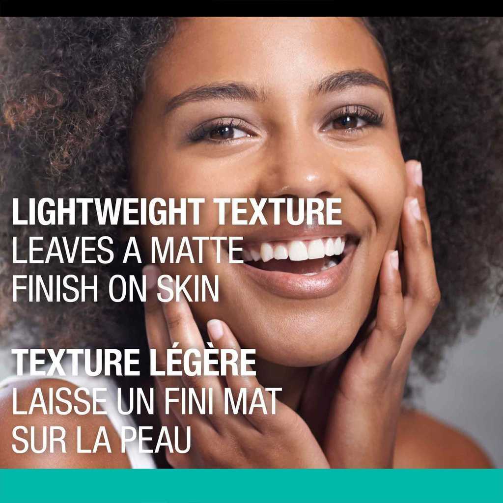 Headshot of a young woman touching her face with her hands while smiling  and product claim 'Lightweight Texture Leaves a Matte Finish on Skin'
