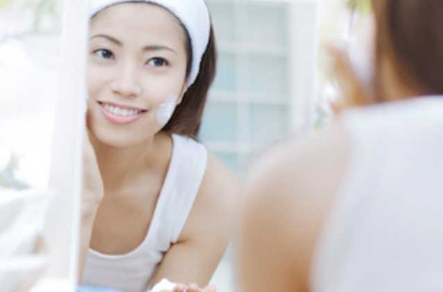 Woman applying NEUTROGENA® moisturizer to face