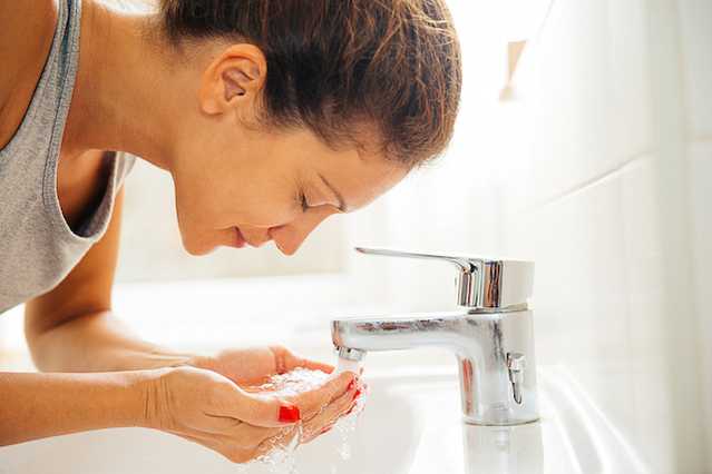 Woman washing her face with NEUTROGENA® products to help treat & prevent acne
