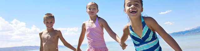 Kids playing on beach and wearing NEUTROGENA® kids sunscreen